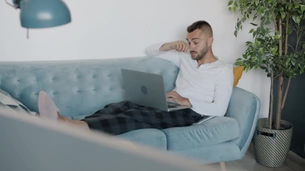 Jeune homme attrayant pigiste travaillant avec un ordinateur portable puis envoyant un message vocal avec smartphone à la maison — Video