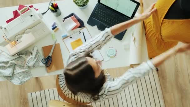 Zeitraffer von oben: Modedesignerin zeichnet Kleidungsstück, das mit Nähmaschine arbeitet und misst Tuch auf Attrappe — Stockvideo