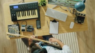 Evde gitar ve klavye çalan genç adamın müzik yaratma zamanının en üst düzeyi