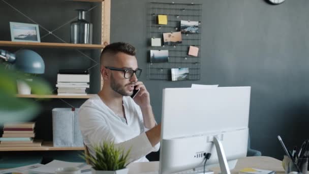 Poważny pracownik biurowy rozmawiający przez telefon komórkowy pracujący sam w biurze — Wideo stockowe