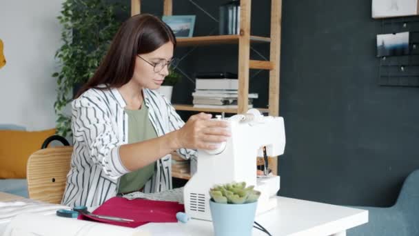 Портрет творческой девушки швейной одежды с электрической машиной наслаждаясь хобби дома — стоковое видео