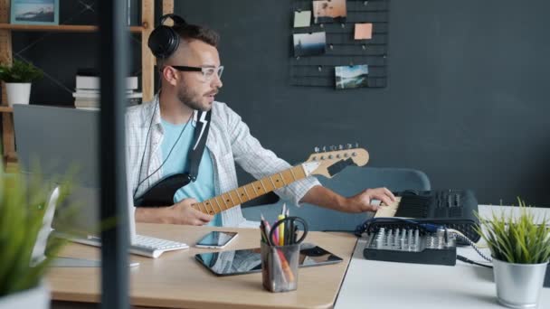 Talentoso cara tocando instrumentos musicais teclado e guitarra gravação de música dentro de estúdio — Vídeo de Stock