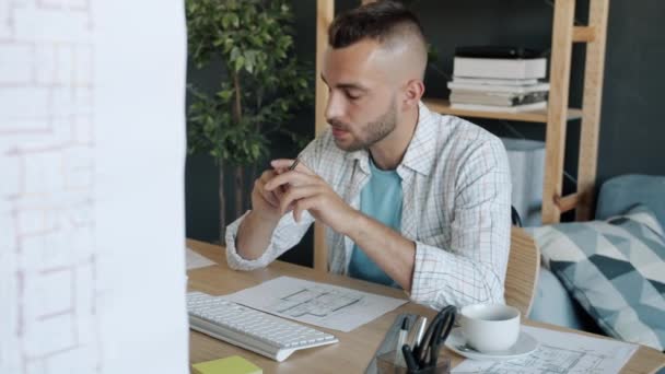 Retrato en cámara lenta de un arquitecto atractivo dibujando un plan de construcción mirando la pantalla del ordenador trabajando en casa — Vídeos de Stock