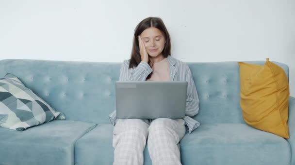 Esausta giovane donna che lavora con il computer portatile a casa sbadigliando braccia tese sensazione di sonnolenza — Video Stock