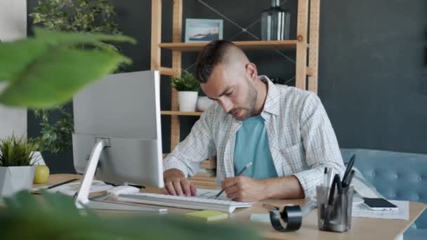 Bilgisayarla çalışan hırslı serbest çalışan bir mimar. Sonra da kağıt üzerinde inşaat planına bakıyor. — Stok video