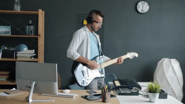 Zpomalený portrét atraktivního muže účinkujícího na kytaru a klávesnici nahrávání hudby — Stock video