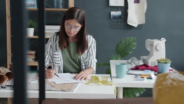 Медленное движение молодой женщины, рисующей стильную одежду, работающей в одной студии моды — стоковое видео