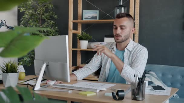 Joven arquitecto profesional estudiando plan de construcción mirando papel y pantalla de computadora trabajando en casa — Vídeos de Stock