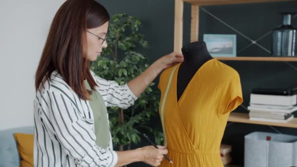 घरी काम टेपसह हस्तनिर्मित ड्रेस मोजण्यासाठी मोहक महिला कपडे डिझायनरचे पोर्ट्रेट — स्टॉक व्हिडिओ