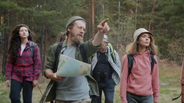 Movimento lento de jovens turistas caminhando na floresta olhando para o mapa e gesticulando discutindo viagem — Vídeo de Stock