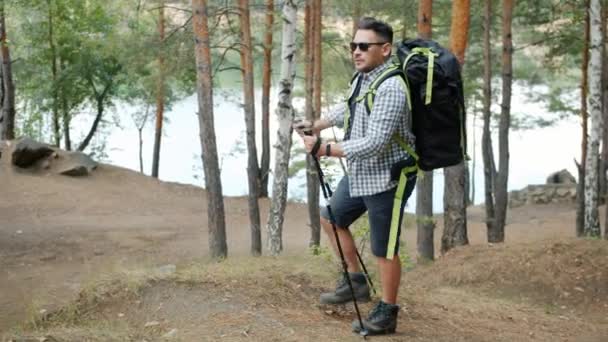Zeitlupe: Junger Mann wandert an Herbsttag mit Rucksack im Wald — Stockvideo