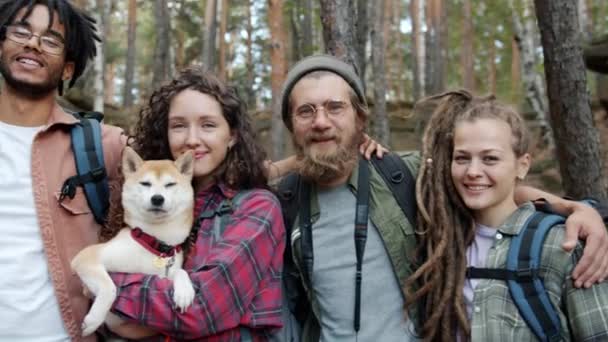 Портрет повільного руху друзів чоловічої та жіночої статі з собакою, що стоїть за межами літнього лісу — стокове відео