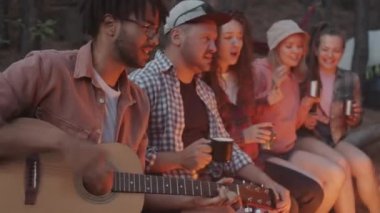 Neşeli gençler gitar eşliğinde şarkı söyleyip dans ediyorlar. Karanlık sonbahar ormanlarında ateşin etrafında oturmuş metal bardaklardan içiyorlar.