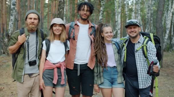 Porträt glücklicher Männer und Frauen, die sich umarmen und lächelnd in die im Wald stehende Kamera schauen — Stockvideo
