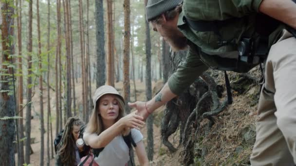 Αργή κίνηση της φροντίδας άνθρωπος τουρίστας βοηθώντας τις γυναίκες φίλους, ενώ το περπάτημα στο δάσος μαζί — Αρχείο Βίντεο