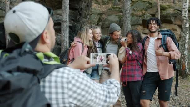 Monirotuinen ryhmä turisteja poseeraa älypuhelin kamera heiluttaa käsiä ja suudella shiba inu koira metsässä — kuvapankkivideo