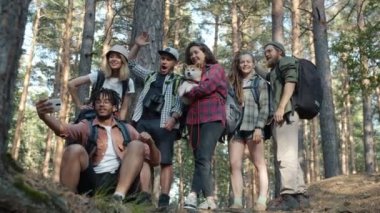 Neşeli genç turistler akıllı telefon kameralarıyla selfie çekiyorlar. El hareketleriyle poz vererek eğleniyorlar.