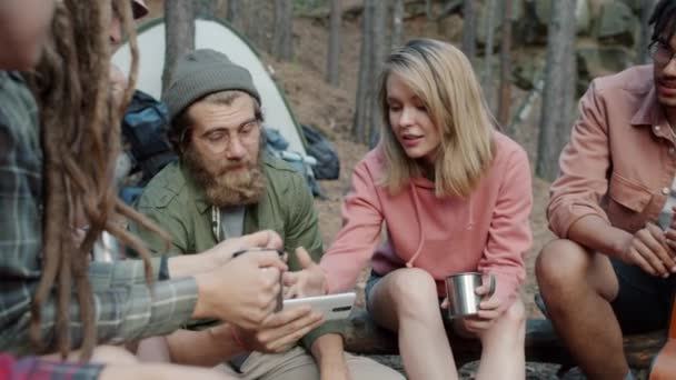 Χαρούμενοι άνθρωποι που χρησιμοποιούν έξυπνο τηλέφωνο πίνοντας από μεταλλικά ποτήρια μιλώντας και γελώντας στην κατασκήνωση στο δάσος — Αρχείο Βίντεο