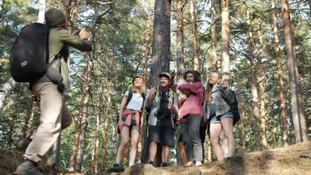 Αργή κίνηση των τουριστών ποζάρουν για την κάμερα στο δάσος διασκεδάζοντας, ενώ ο άνθρωπος με σακίδιο λήψη φωτογραφιών — Αρχείο Βίντεο