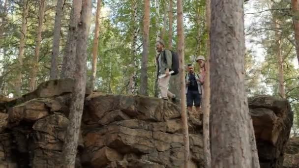 Movimento lento de turistas andando em montanhas olhando ao redor através de binóculos segurando mapa — Vídeo de Stock