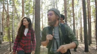 Çok ırklı arkadaş grubu güneşli bir yaz gününde ormanda yürüyüp gezinin tadını çıkarıyor.