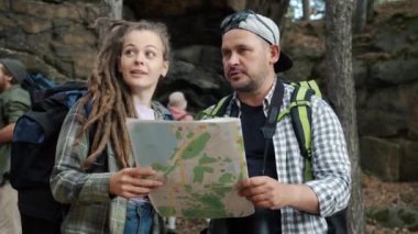 Bir grup turist haritaya bakıyor ve ormanda ayakta durmayı tartışıyorlar.