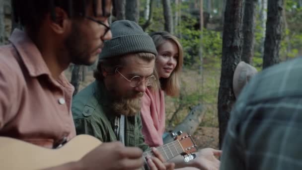 Νέοι άνδρες και γυναίκες τουρίστες τραγουδούν τραγούδια για κιθάρα απολαμβάνοντας το Σαββατοκύριακο στο δάσος του φθινοπώρου — Αρχείο Βίντεο