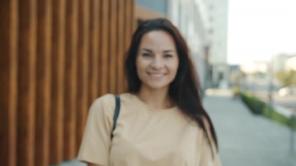 Zoom-in portret van zorgeloze jonge brunette staan buiten in stedelijke straat in de zomer — Stockvideo