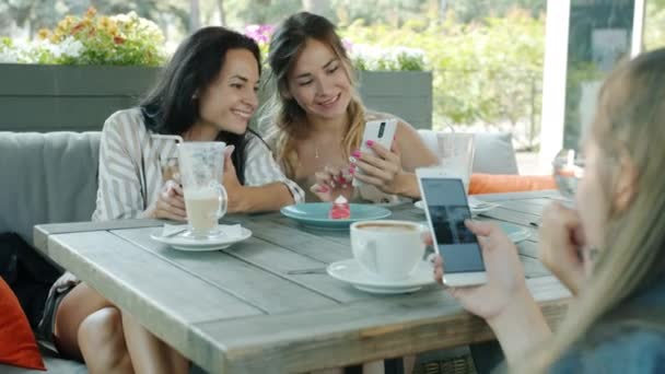 Meninas alegres amigos olhando para a tela do smartphone deslizando se divertindo no café desfrutando de conteúdo — Vídeo de Stock