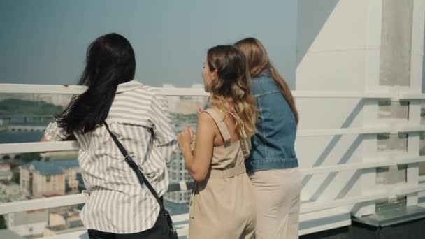 Joyful young women tourists standing on balcony and watching beautiful city talking enjoying summer day — Stock Video