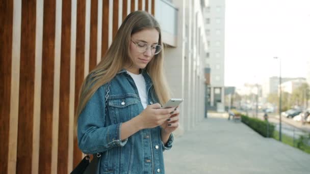 Menina alegre usando smartphone, em seguida, encontrar amigo rindo abraço enjoyng encontro na cidade moderna — Vídeo de Stock