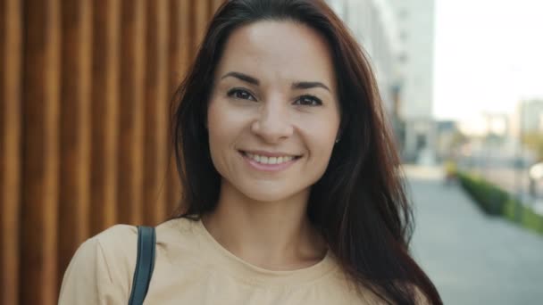 Zoom-out portret van een aantrekkelijke dame buiten in de stad straat glimlachend kijkend naar camera — Stockvideo