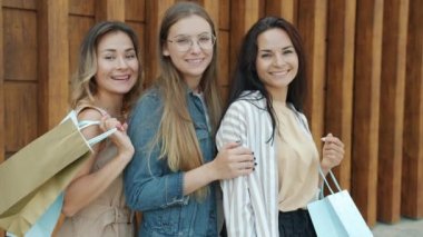 Güzel genç bayan müşterilerin portresi. Sokakta ellerinde kağıt torbalarla durup gülümsüyorlar.