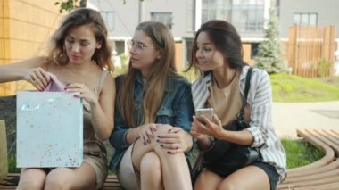 Dışarda oturup kağıt torbalarla alışveriş yapan genç ve mutlu kadınların yavaş çekimleri.