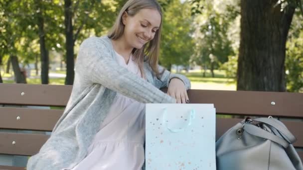 Framtidens mamma tittar på barnskor ha kul med stövlar gå på magen leende i stadsparken — Stockvideo