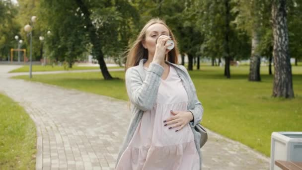 Joyeux jeune femme enceinte marchant dans le parc profiter d'aller boire un verre le jour d'été — Video