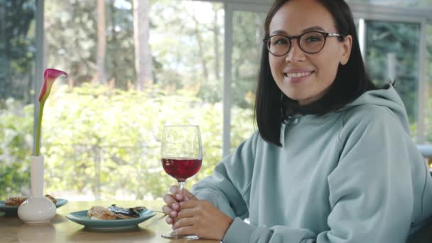 Zpomalený pohyb atraktivní mladé dámy s úsměvem drží sklenici vína sedí u stolu v kavárně s jídlem a dezerty — Stock video