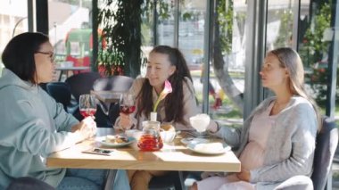 Kadeh kaldıran, kadeh tokuşturan ve bardakları tokuşturan bir grup kadın şehrin rahat kafesinde günün tadını çıkarıyor.