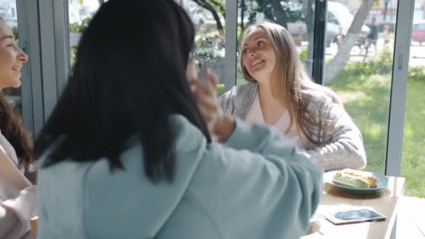 Futura mãe feliz recebendo presentes sapatos de bebê de amigos carinhosos no café de verão — Vídeo de Stock