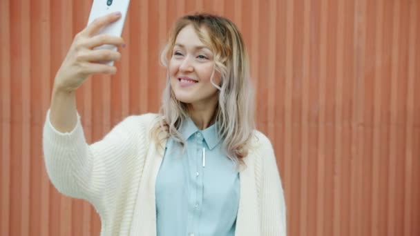 Linda senhora tomando selfie com câmera de smartphone posando com grimeiras engraçadas de pé ao ar livre — Vídeo de Stock