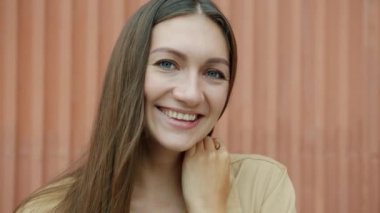 Çekici genç bayanın yakın plan portresi gülümseyen ve kameraya neşe ve neşe ile bakan.
