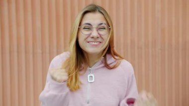 Yavaş çekim portresi. Duygusal kadın yumruklarını sallıyor ve dışarıdaki kızgın ve komik yüzüyle kameraya bakıyor.