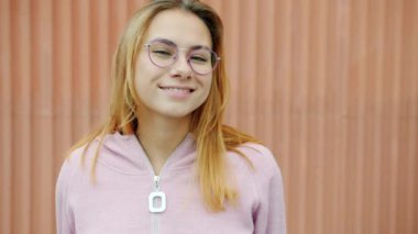 Açık havada kameraya gülümseyen güzel bir genç bayanın yavaş çekim portresi.