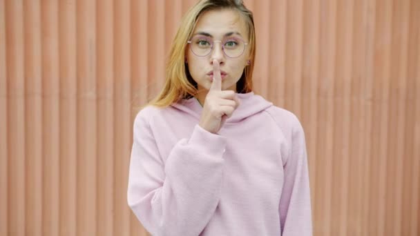 Slow motion portrait of cute blonde hushing touching mouth with forefinger outdoors — Stock Video