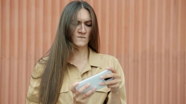 Emotionele jonge vrouw gamer spelen smartphone video game plezier buiten — Stockvideo