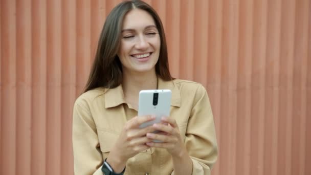 Portret van vrolijke vrouw met behulp van smartphone lachen genieten van social media communicatie buiten — Stockvideo