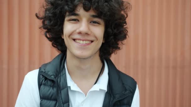 Slow motion portrait of handsome young brunet with curly hair smiling outdoors — Stock Video