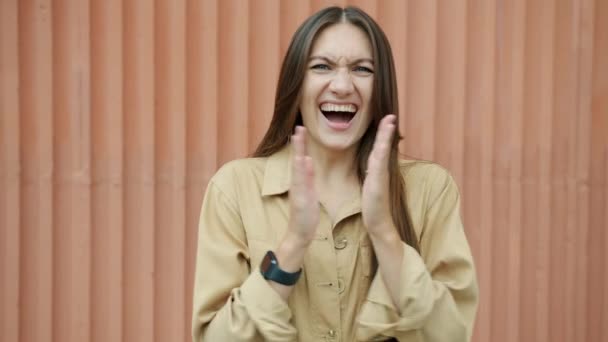 Zeitlupe eines fröhlichen Mädchens, das lacht und mit den Fingern klatscht, wenn es draußen steht und in die Kamera blickt — Stockvideo