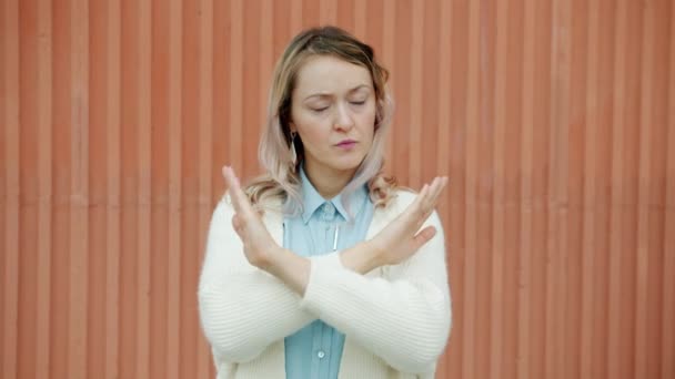 Zeitlupenporträt einer ernsthaften jungen Frau, die die Arme verschränkt und streng in die Kamera blickt — Stockvideo