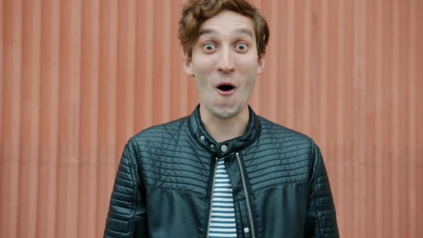 Portrait d'un homme excité riant ouvrant la bouche exprimant bonheur et étonnement à l'extérieur sur fond urbain — Video